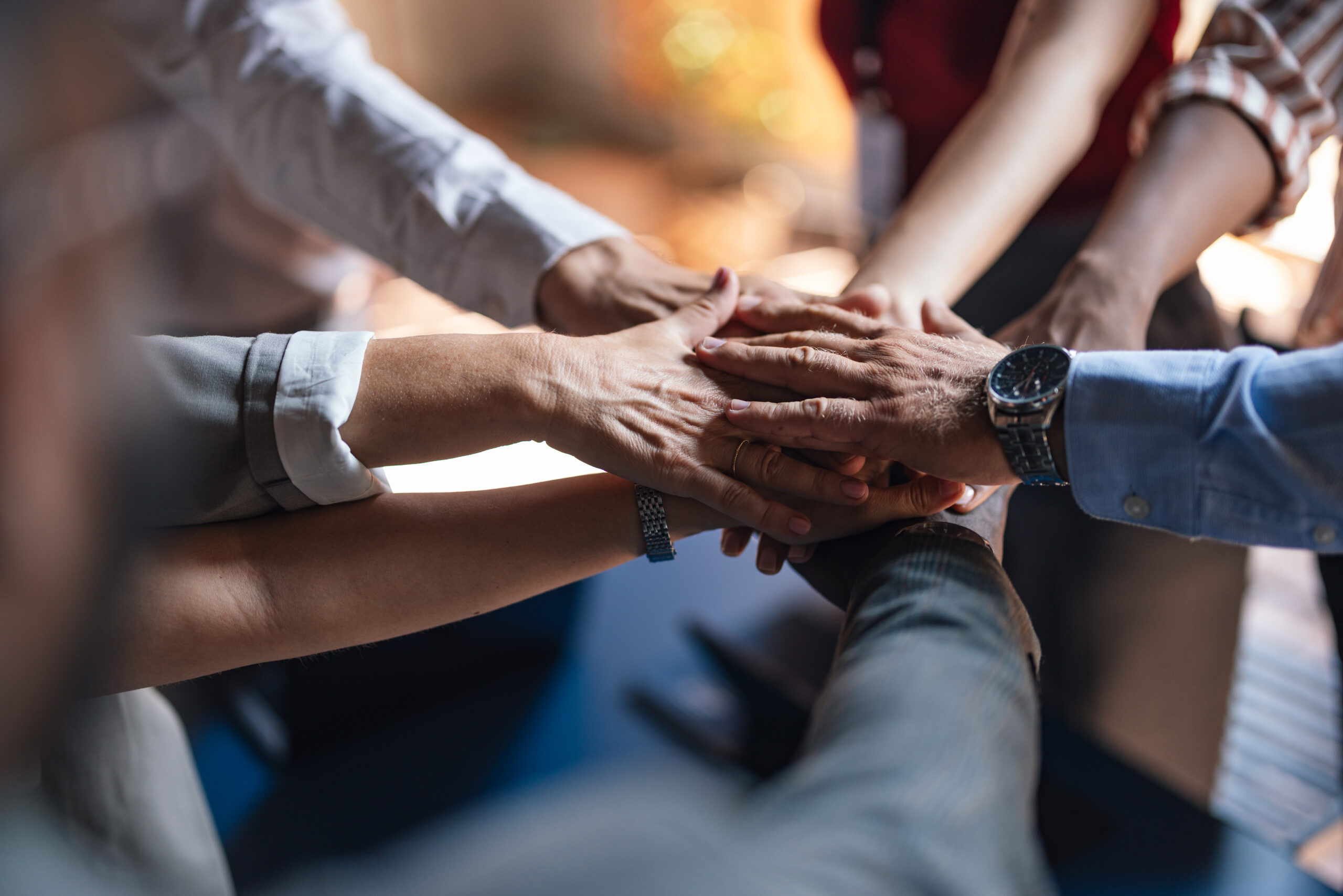 A close-up image of hands overlapping in a gesture of teamwork and unity
