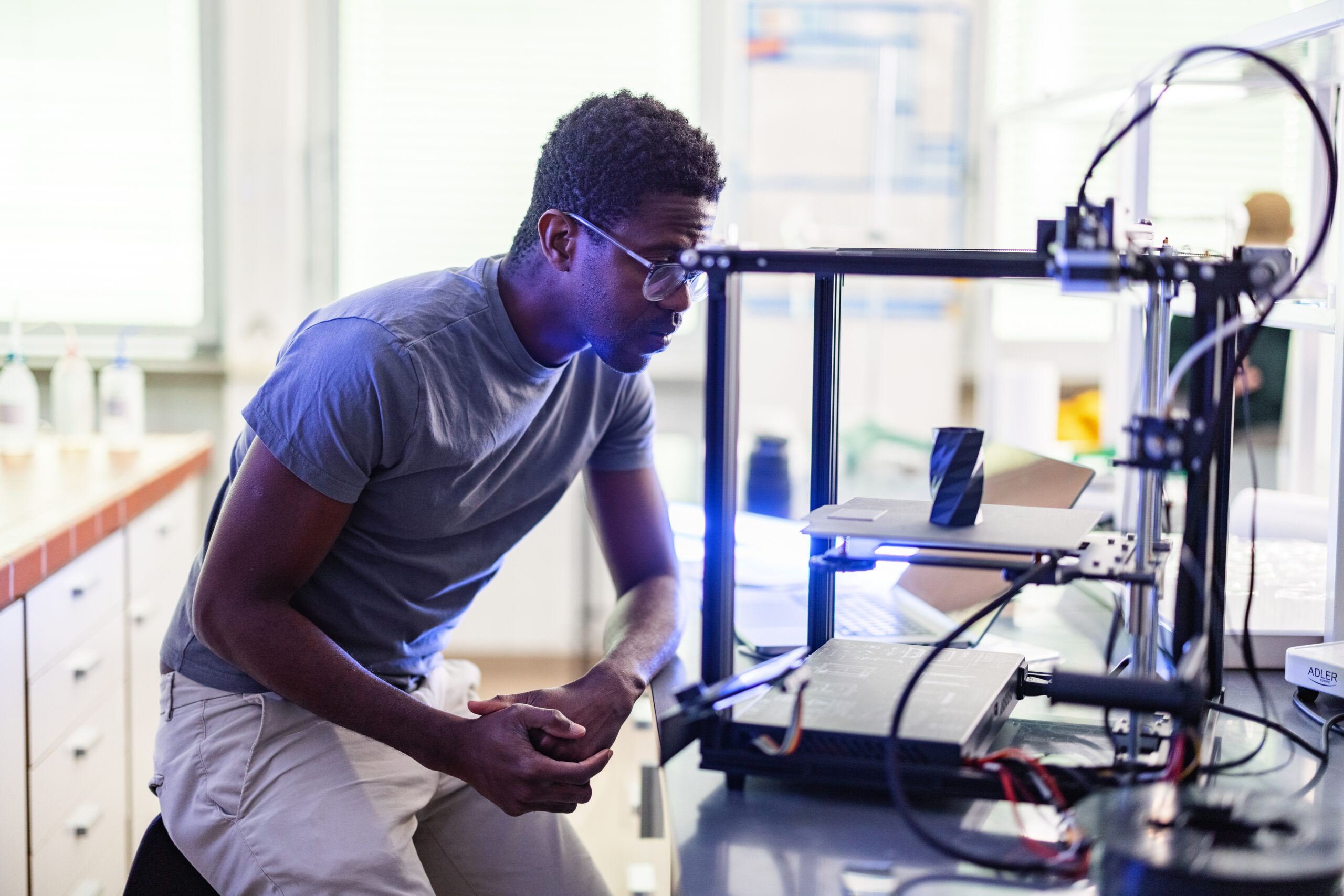 Male engineering student looking at 3D printer