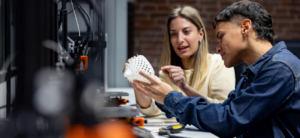 Two college students look at an 3D-printed object that they made.