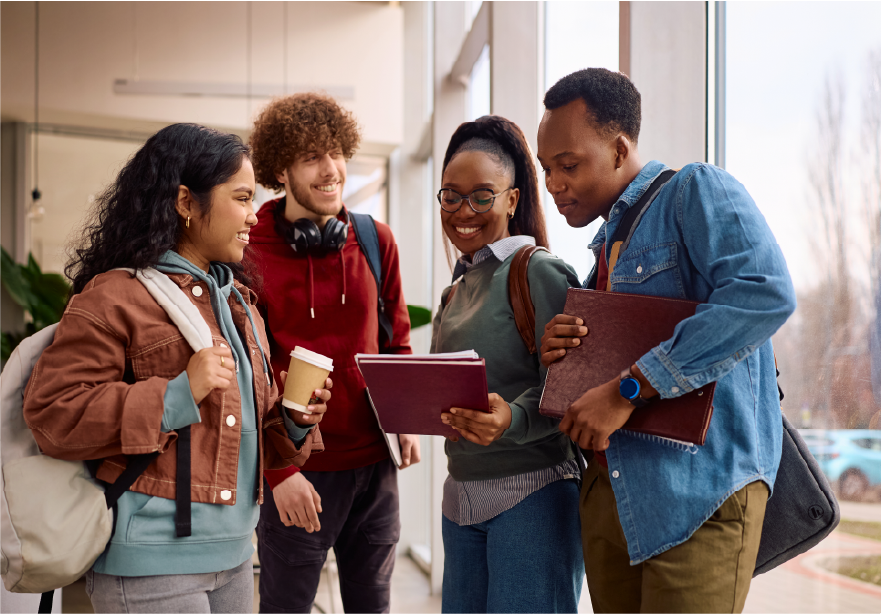 Smiling college students look a piece of paper on top of a notebook.