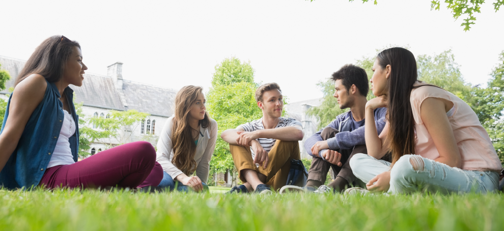 A group of students enjoying each other's company while sitting outside.