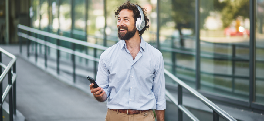 A business man walking while listening to a podcast on his phone.
